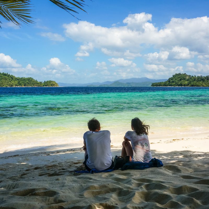 a person sitting on a beach near a body of water