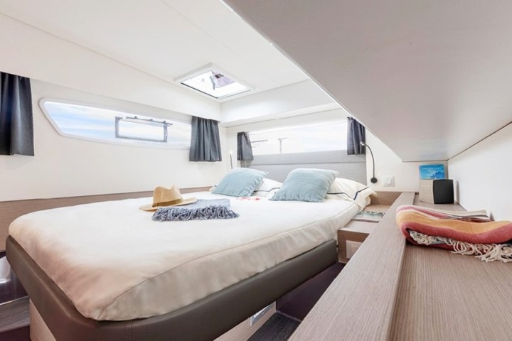 Cozy boat cabin with a double bed, pillows, skylight, and nautical decor.