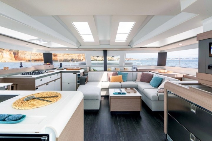 Luxurious yacht interior with modern kitchen, sofa, and large windows overlooking the ocean.